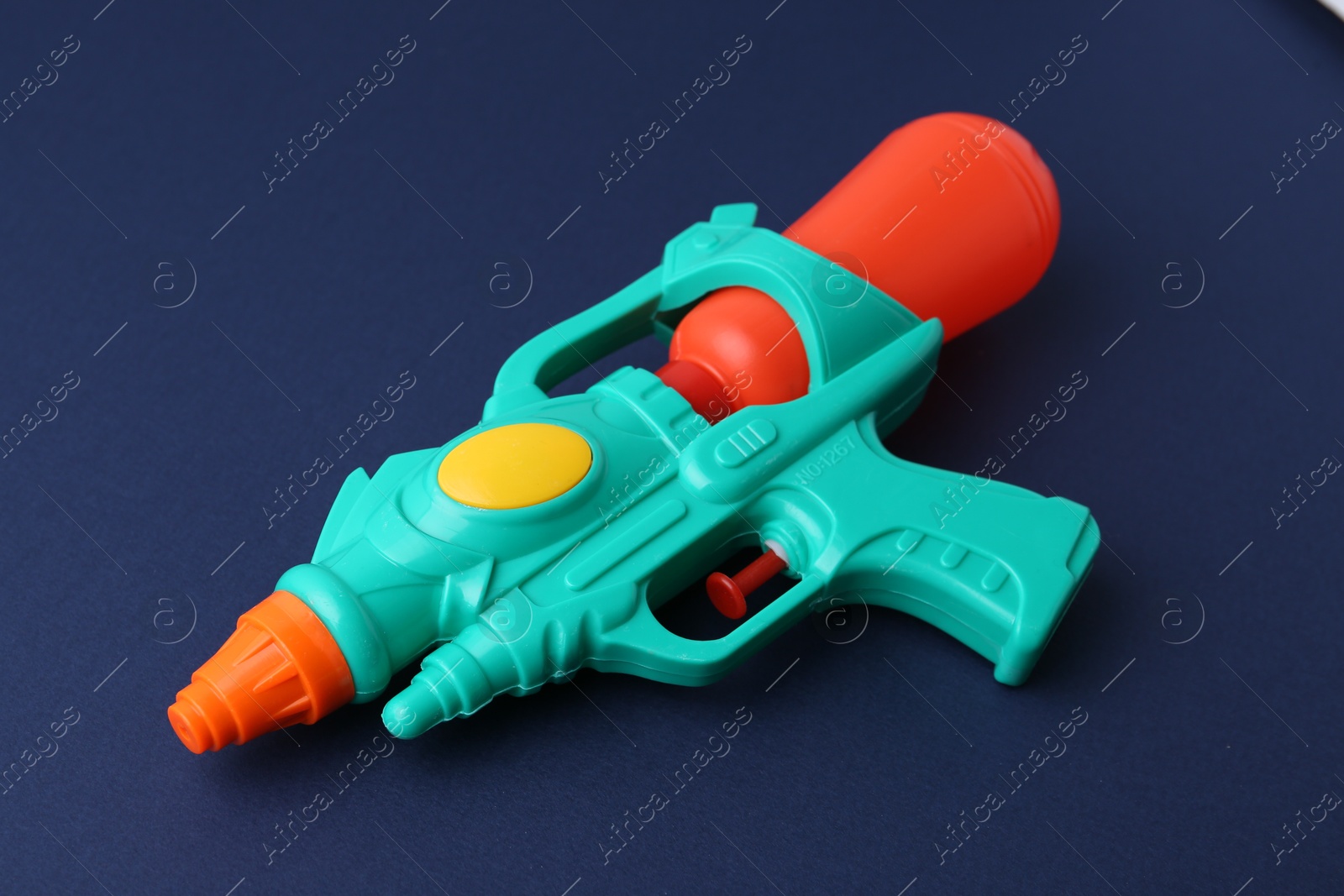 Bright plastic water gun on dark blue background, closeup Photo of Bright plastic water gun on dark blue background, closeup