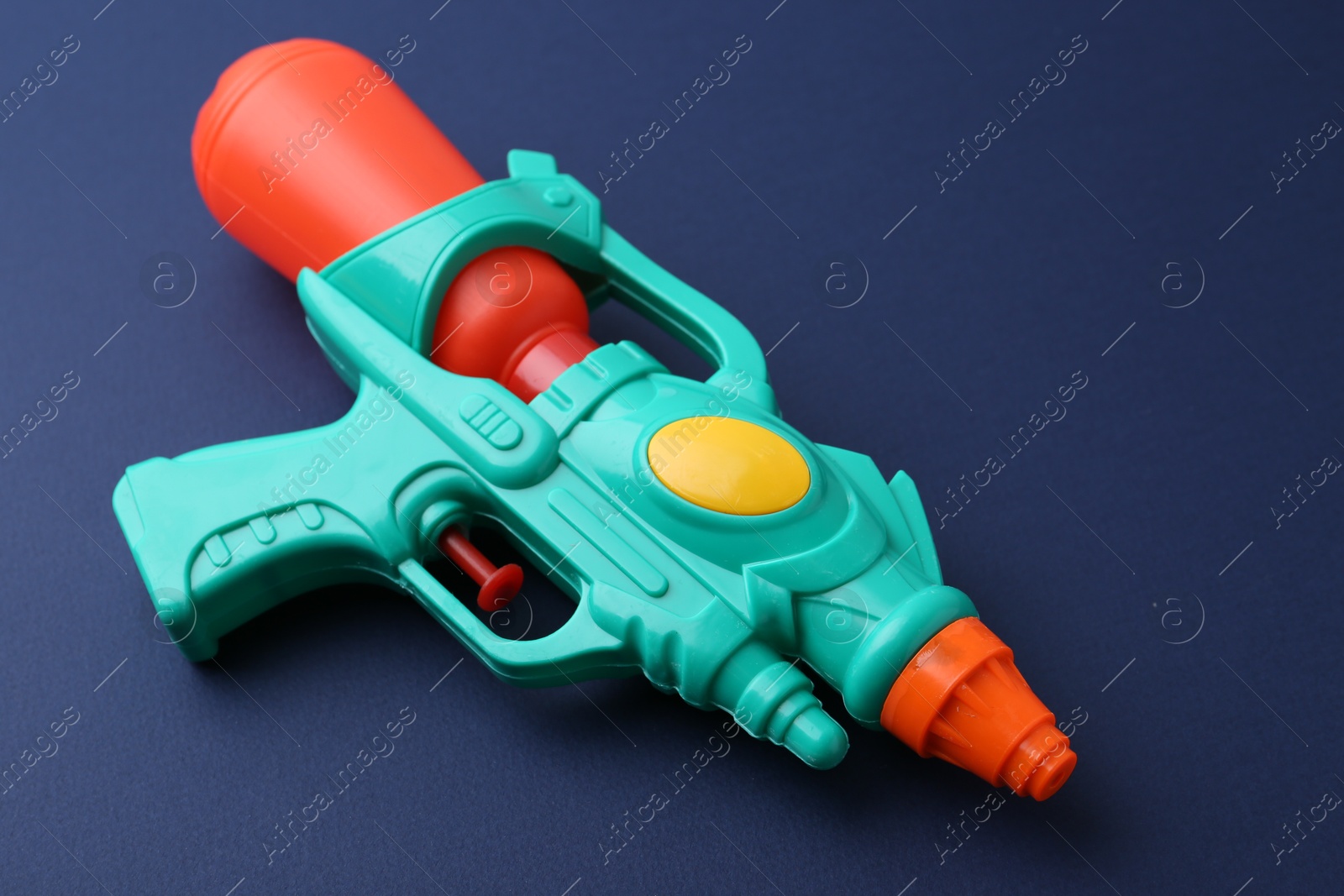 Bright plastic water gun on dark blue background, closeup Photo of Bright plastic water gun on dark blue background, closeup