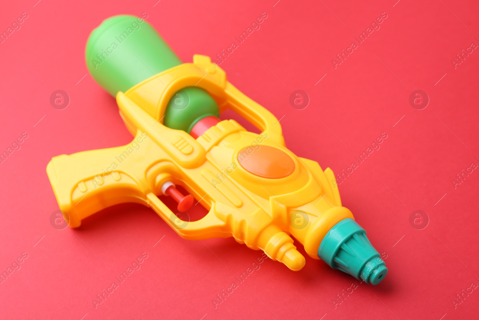 Bright plastic water gun on red background, closeup Photo of Bright plastic water gun on red background, closeup
