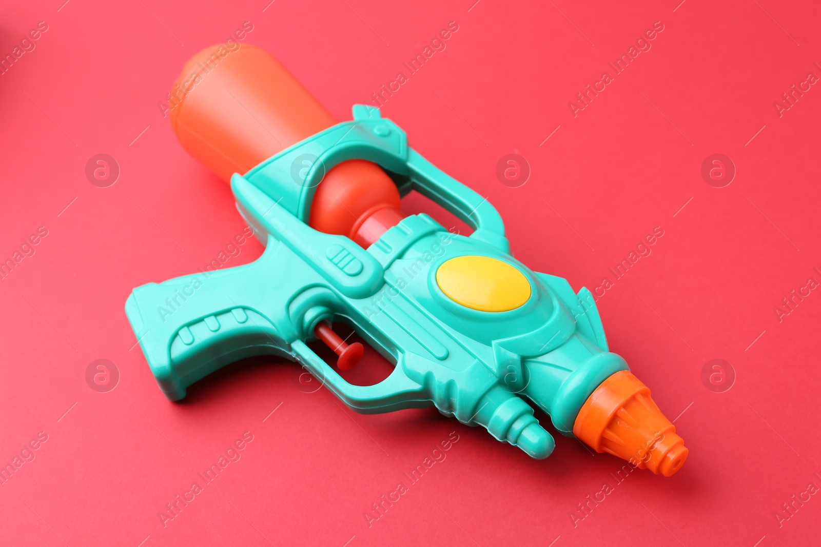 Bright plastic water gun on red background, closeup Photo of Bright plastic water gun on red background, closeup