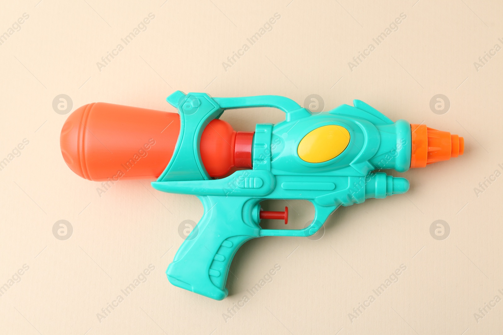 Bright plastic water gun on beige background, top view Photo of Bright plastic water gun on beige background, top view