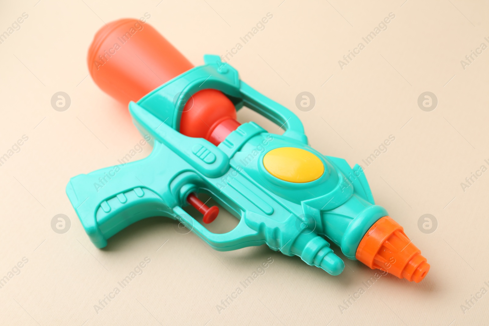 Bright plastic water gun on beige background, closeup Photo of Bright plastic water gun on beige background, closeup