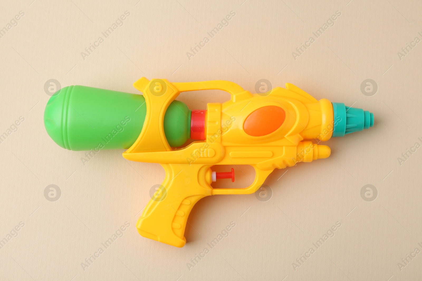 Bright plastic water gun on beige background, top view Photo of Bright plastic water gun on beige background, top view