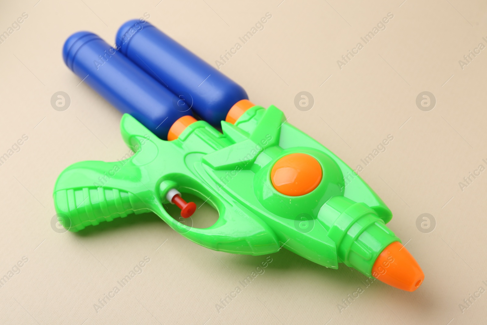 Bright plastic water gun on beige background, closeup Photo of Bright plastic water gun on beige background, closeup