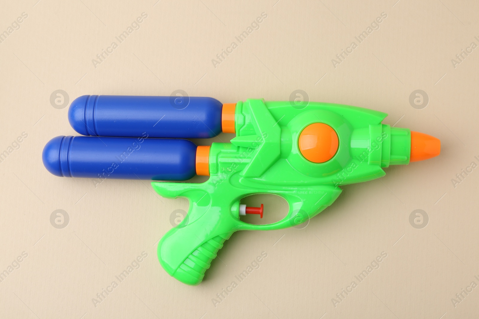 Bright plastic water gun on beige background, top view Photo of Bright plastic water gun on beige background, top view