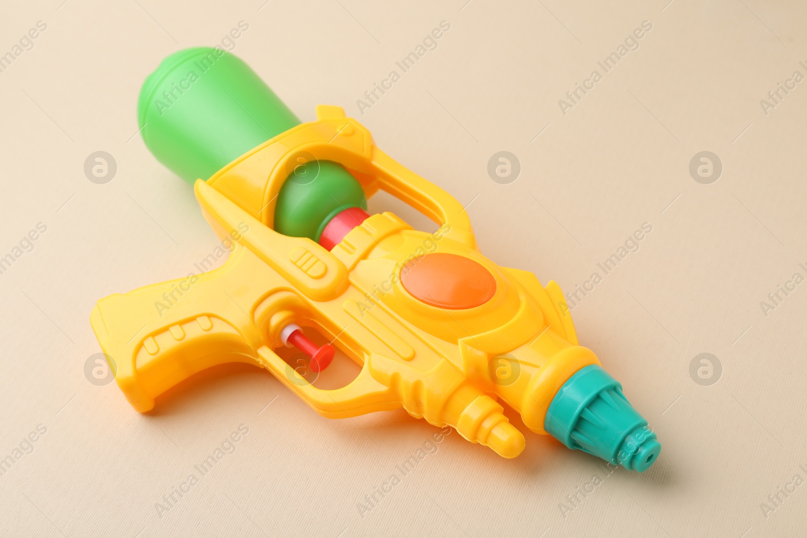 Bright plastic water gun on beige background, closeup Photo of Bright plastic water gun on beige background, closeup