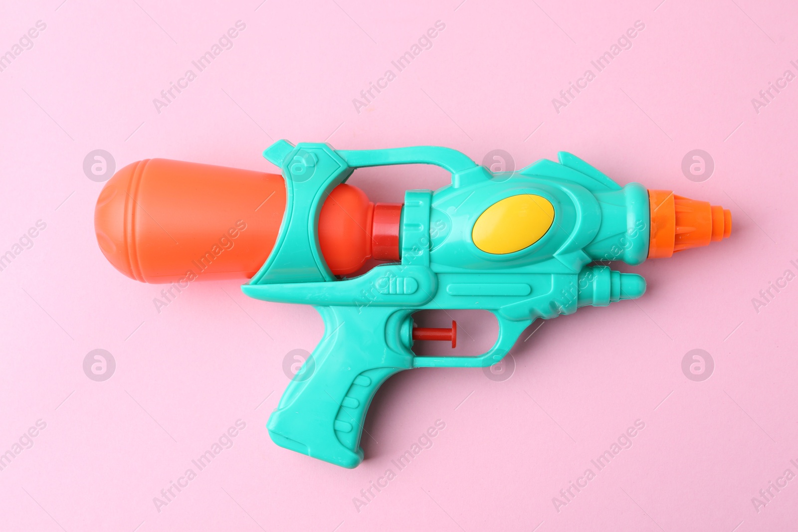 Bright plastic water gun on light pink background, top view Photo of Bright plastic water gun on light pink background, top view