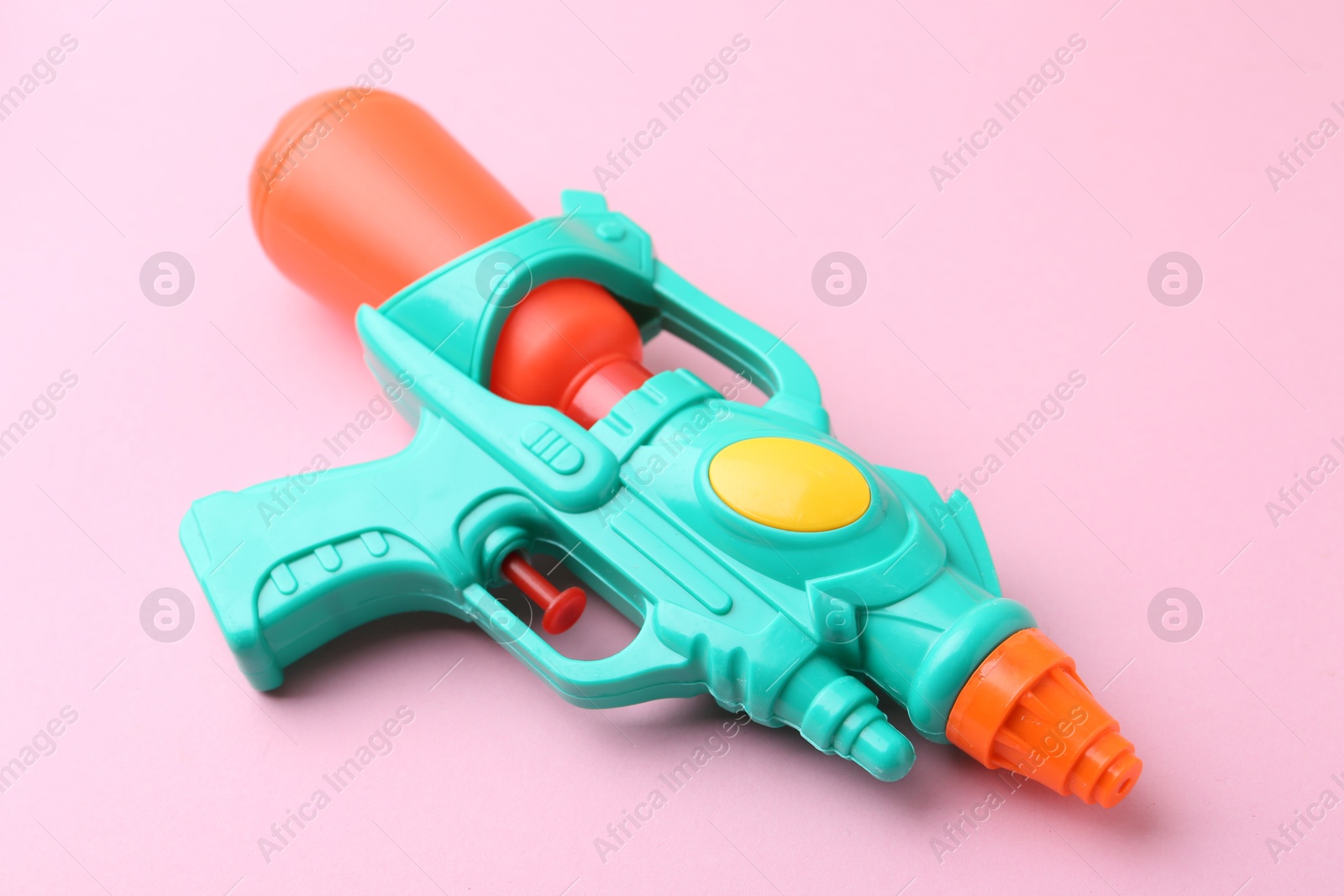 Bright plastic water gun on light pink background, closeup Photo of Bright plastic water gun on light pink background, closeup