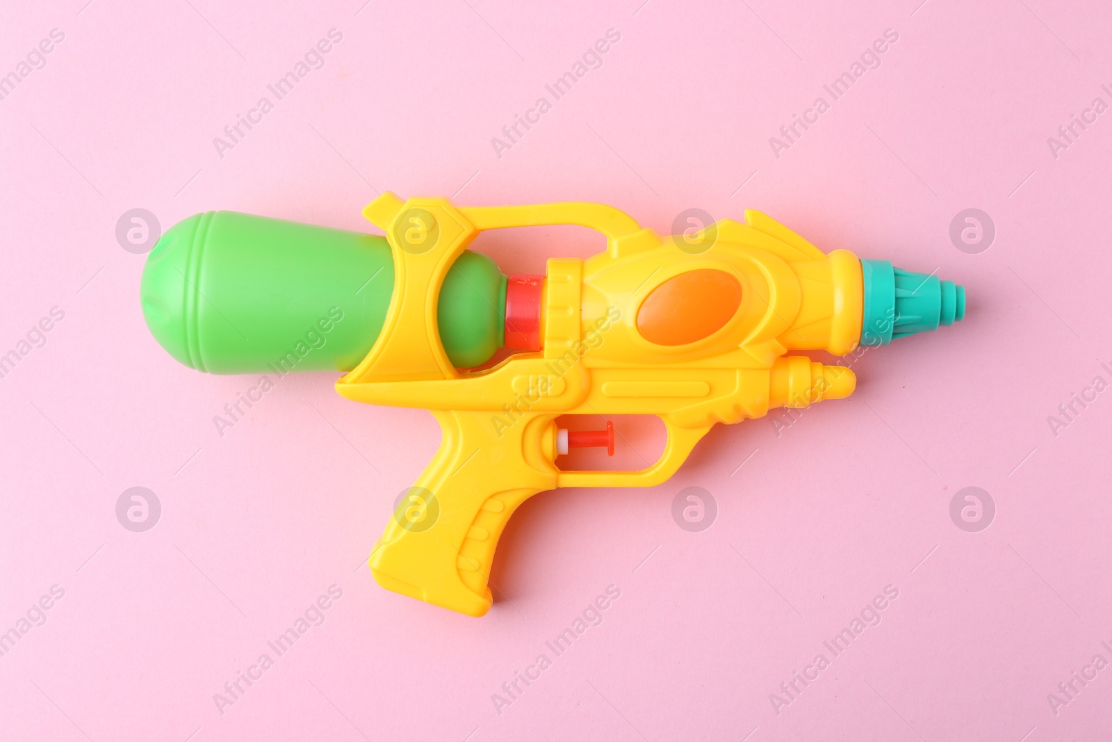 Bright plastic water gun on light pink background, top view Photo of Bright plastic water gun on light pink background, top view