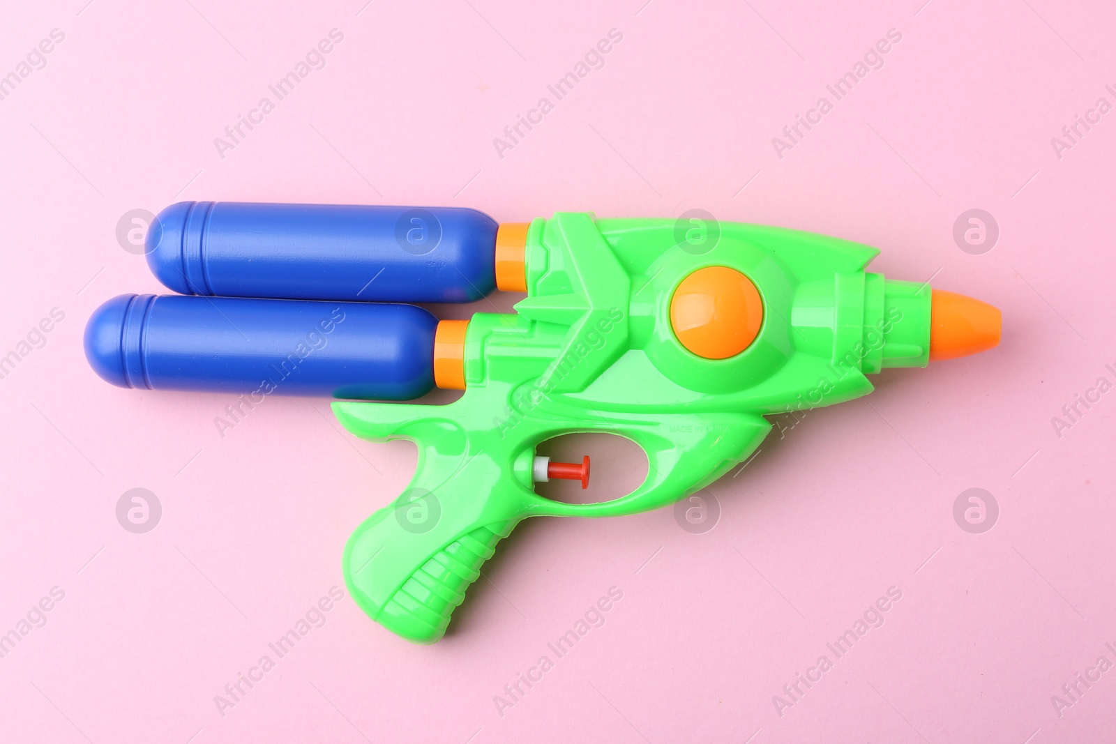 Bright plastic water gun on light pink background, top view Photo of Bright plastic water gun on light pink background, top view