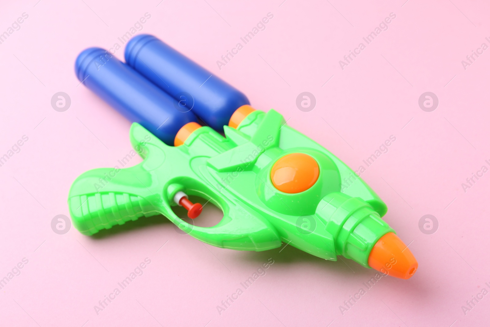 Bright plastic water gun on light pink background, closeup Photo of Bright plastic water gun on light pink background, closeup