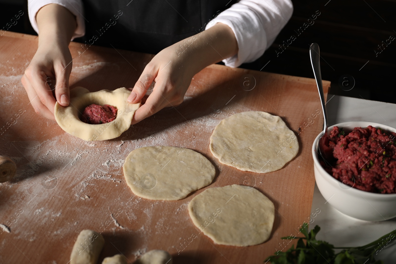 Woman making khinkali on table in kitchen, closeup Photo of Woman making khinkali on table in kitchen, closeup