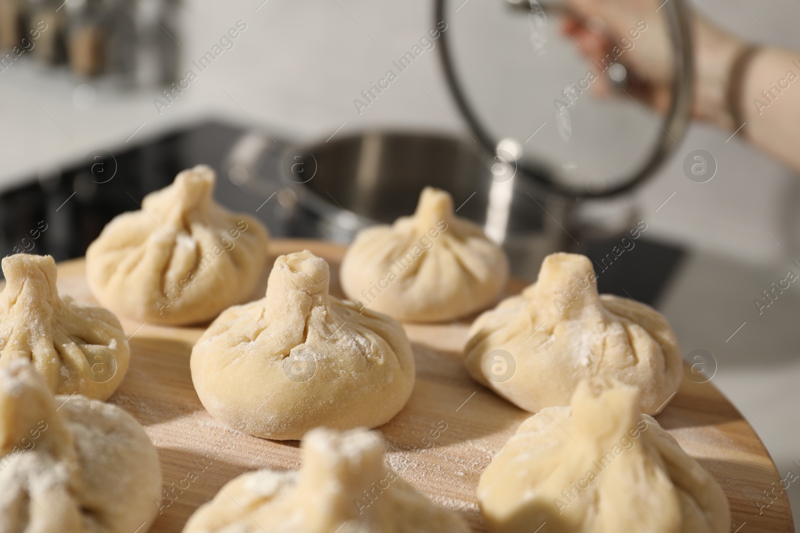 Woman with many uncooked khinkali in kitchen, closeup Photo of Woman with many uncooked khinkali in kitchen, closeup