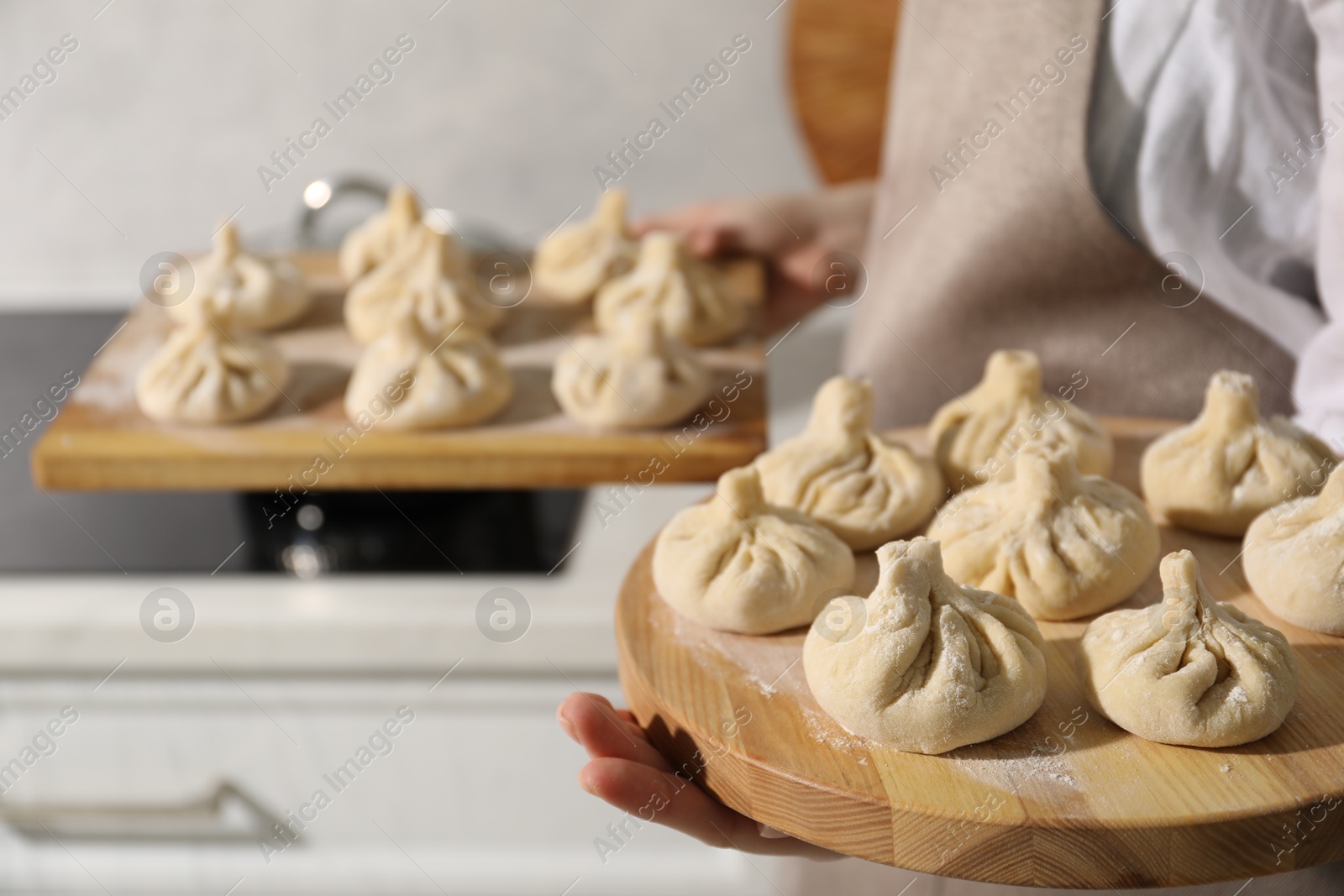 Woman with many uncooked khinkali in kitchen, closeup Photo of Woman with many uncooked khinkali in kitchen, closeup