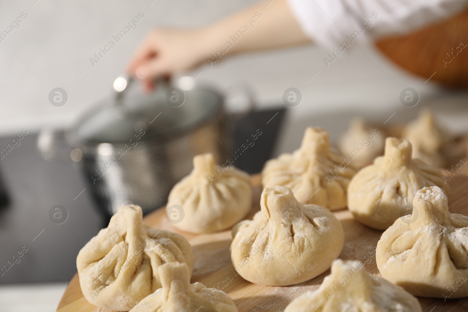 Woman with many uncooked khinkali near cooktop in kitchen, closeup Photo of Woman with many uncooked khinkali near cooktop in kitchen, closeup