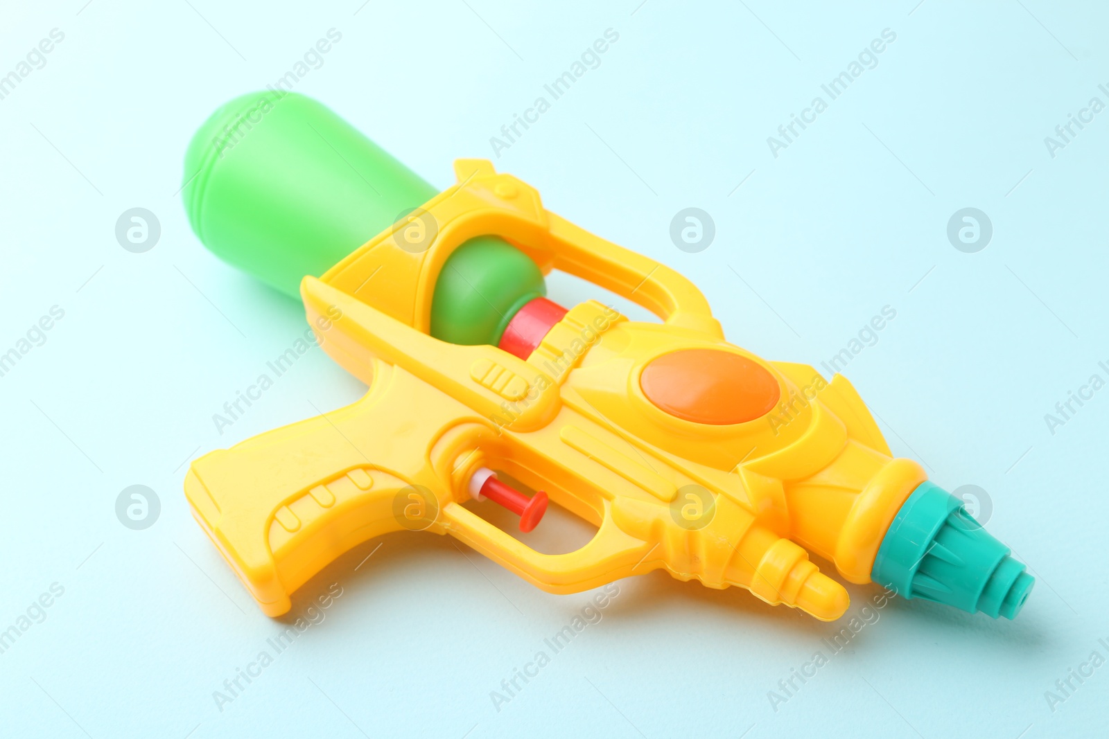 Bright plastic water gun on light blue background, closeup Photo of Bright plastic water gun on light blue background, closeup