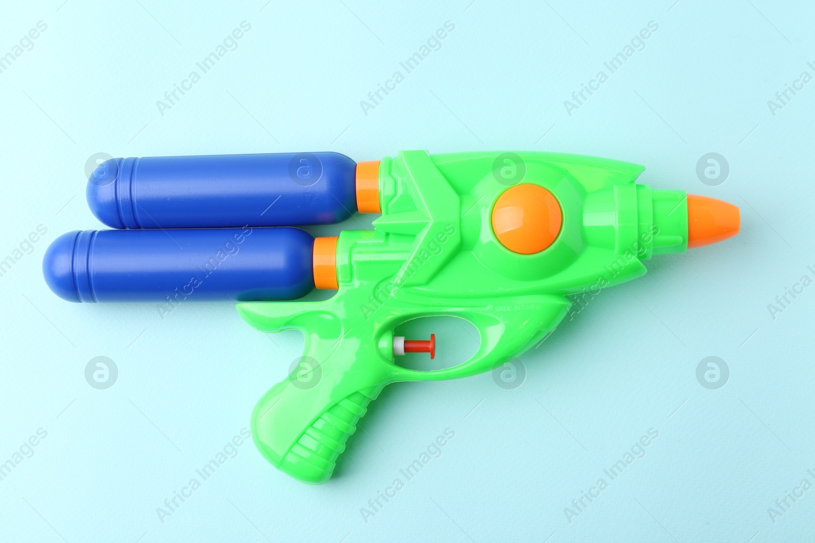 Bright plastic water gun on light blue background, top view Photo of Bright plastic water gun on light blue background, top view