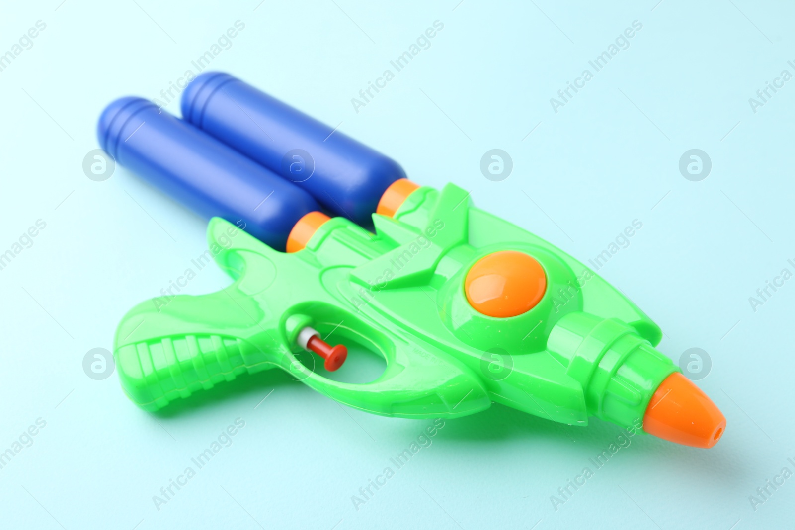 Bright plastic water gun on light blue background, closeup Photo of Bright plastic water gun on light blue background, closeup