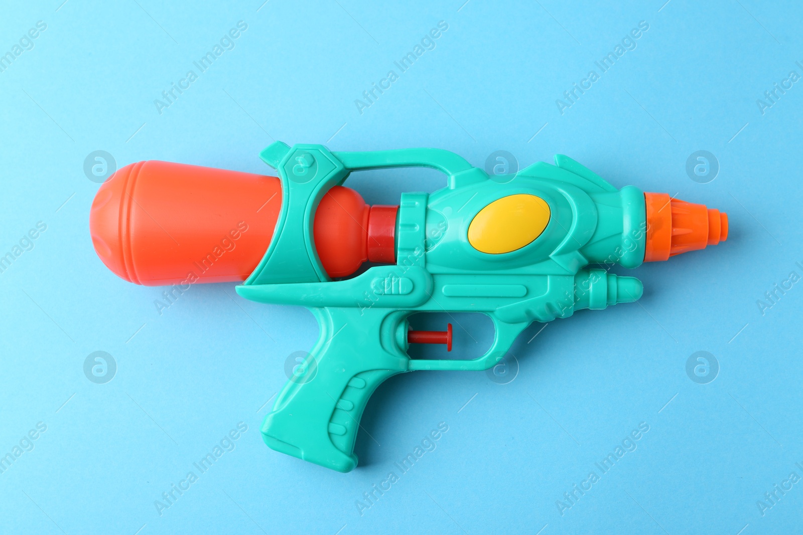 Bright plastic water gun on light blue background, top view Photo of Bright plastic water gun on light blue background, top view