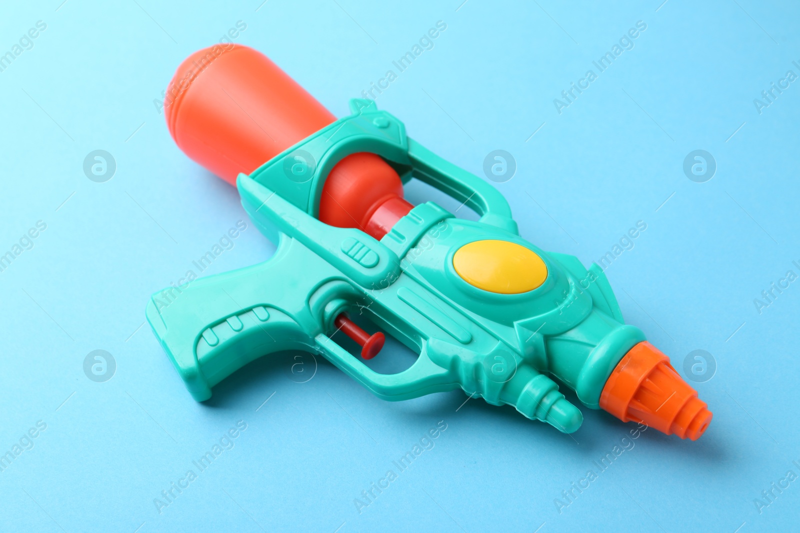 Bright plastic water gun on light blue background, closeup Photo of Bright plastic water gun on light blue background, closeup
