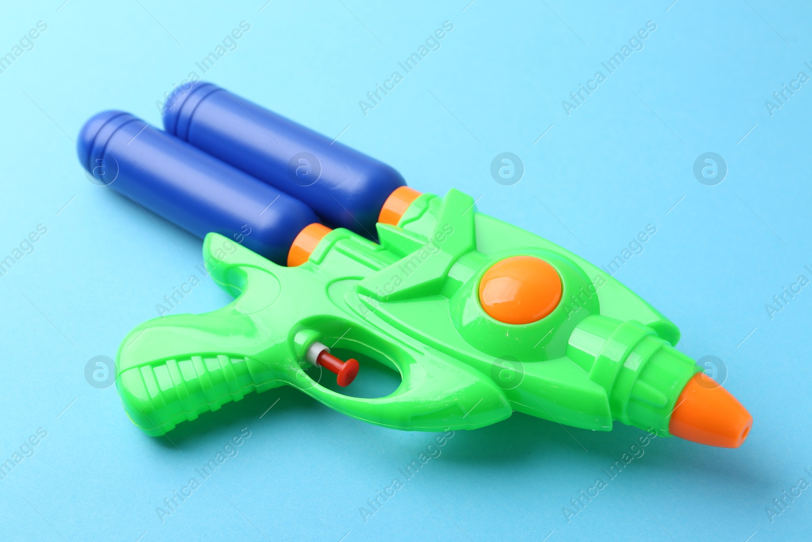 Bright plastic water gun on light blue background, closeup Photo of Bright plastic water gun on light blue background, closeup