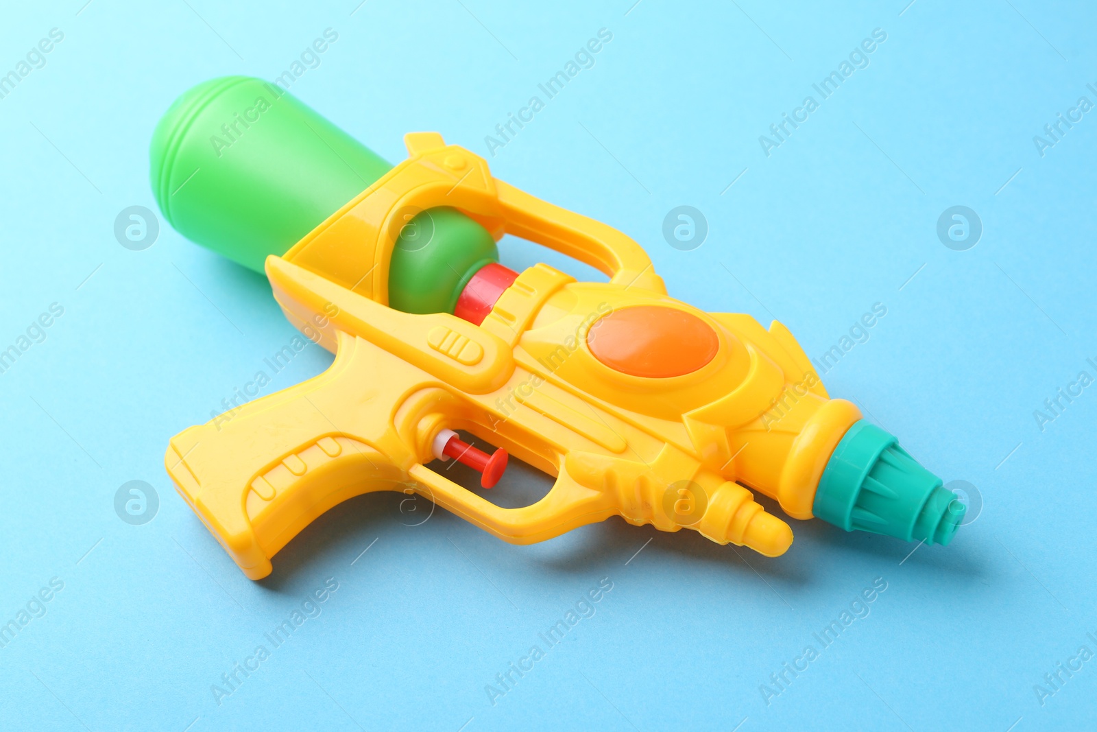 Bright plastic water gun on light blue background, closeup Photo of Bright plastic water gun on light blue background, closeup