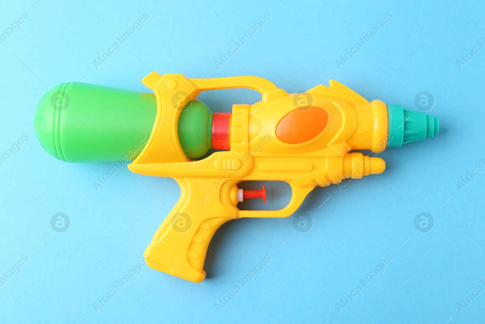 Bright plastic water gun on light blue background, top view Photo of Bright plastic water gun on light blue background, top view