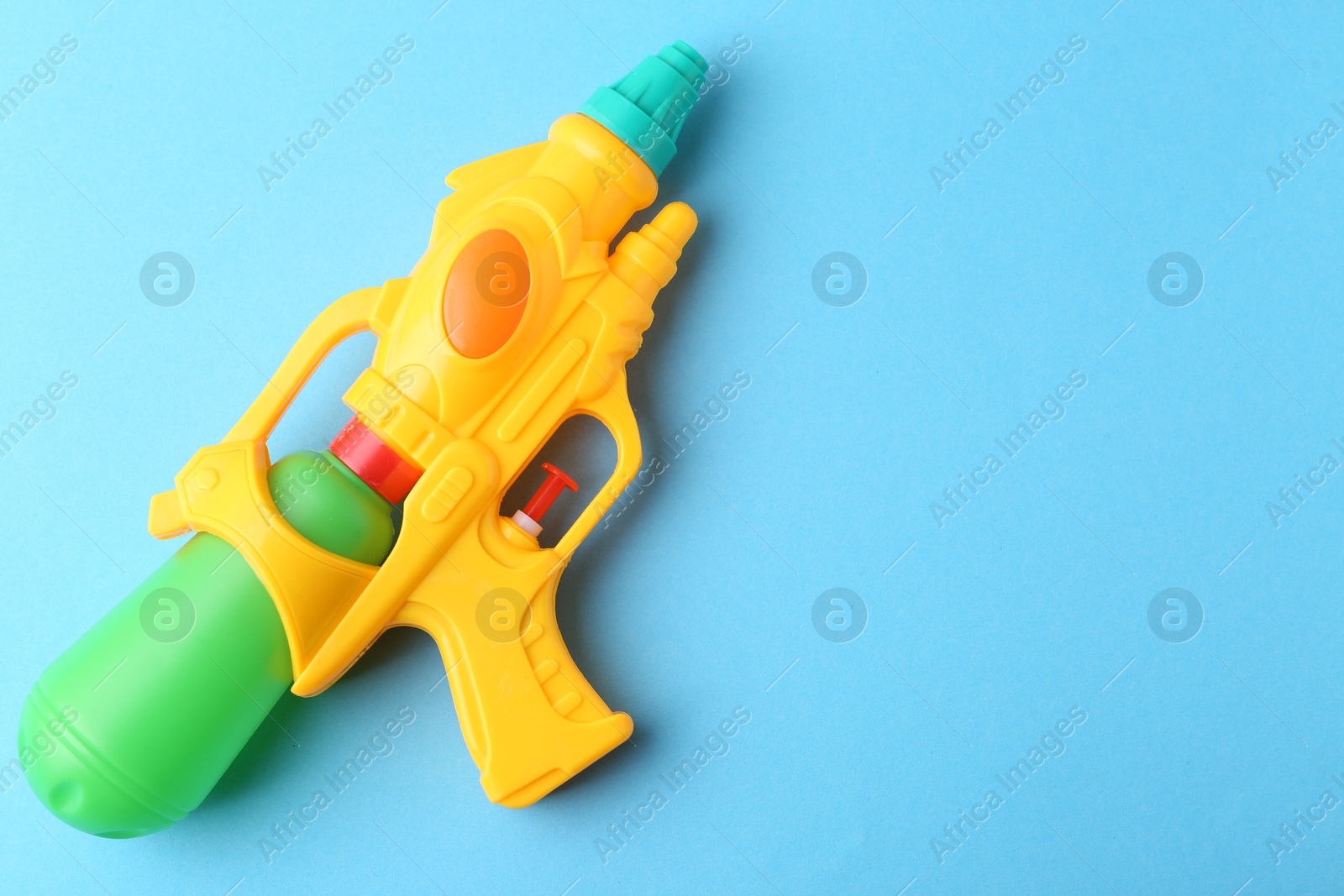 Bright plastic water gun on light blue background, top view. Space for text Photo of Bright plastic water gun on light blue background, top view. Space for text