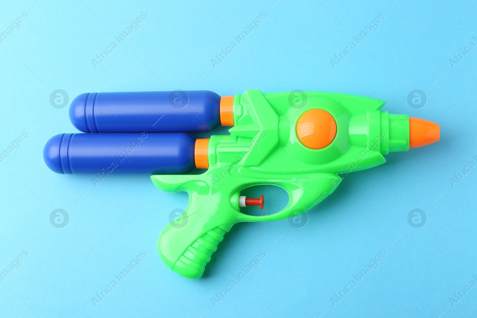 Bright plastic water gun on light blue background, top view Photo of Bright plastic water gun on light blue background, top view