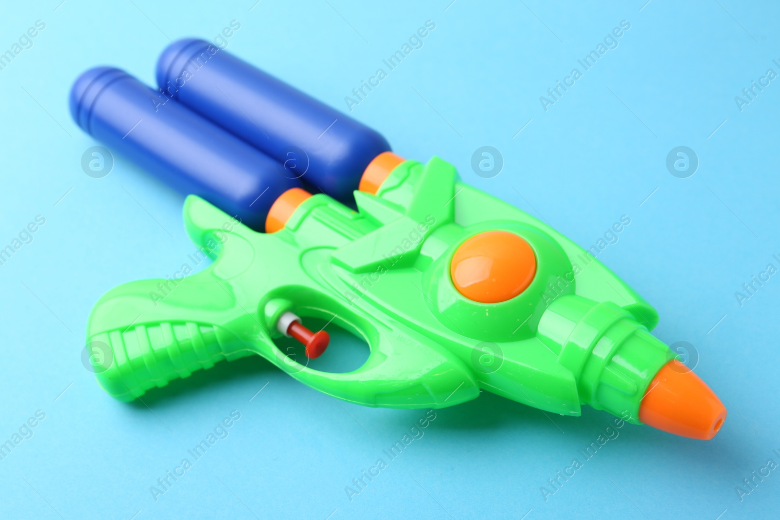 Bright plastic water gun on light blue background, closeup Photo of Bright plastic water gun on light blue background, closeup