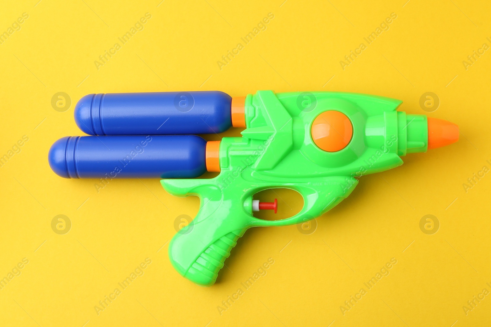 Bright plastic water gun on yellow background, top view Photo of Bright plastic water gun on yellow background, top view