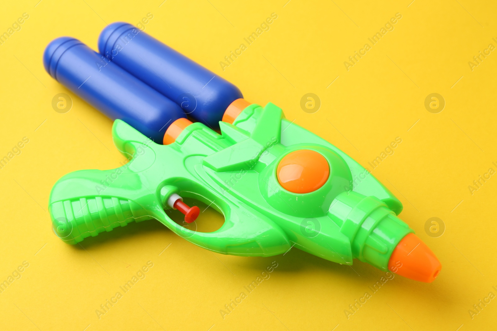 Bright plastic water gun on yellow background, closeup Photo of Bright plastic water gun on yellow background, closeup