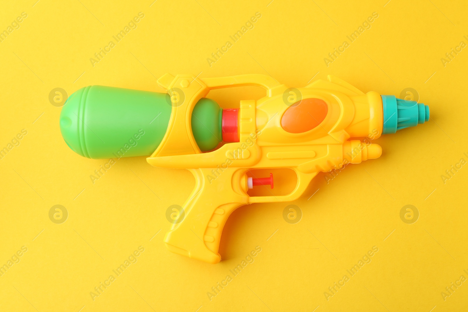 Bright plastic water gun on yellow background, top view Photo of Bright plastic water gun on yellow background, top view