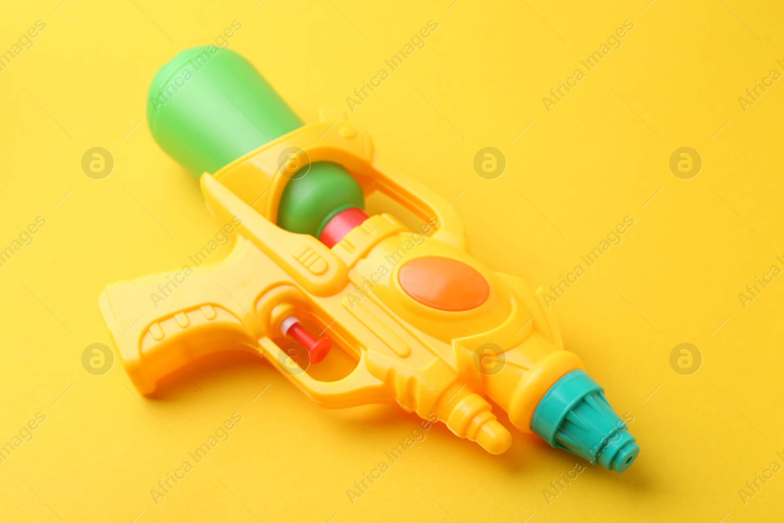 Bright plastic water gun on yellow background, closeup Photo of Bright plastic water gun on yellow background, closeup