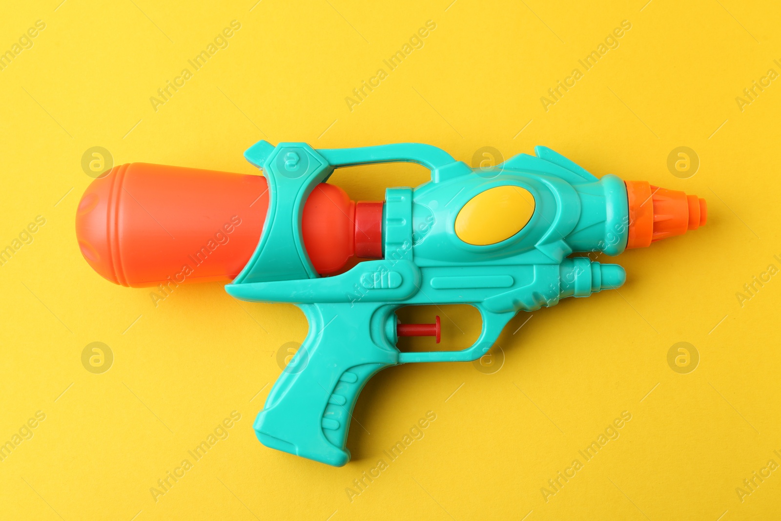Bright plastic water gun on yellow background, top view Photo of Bright plastic water gun on yellow background, top view
