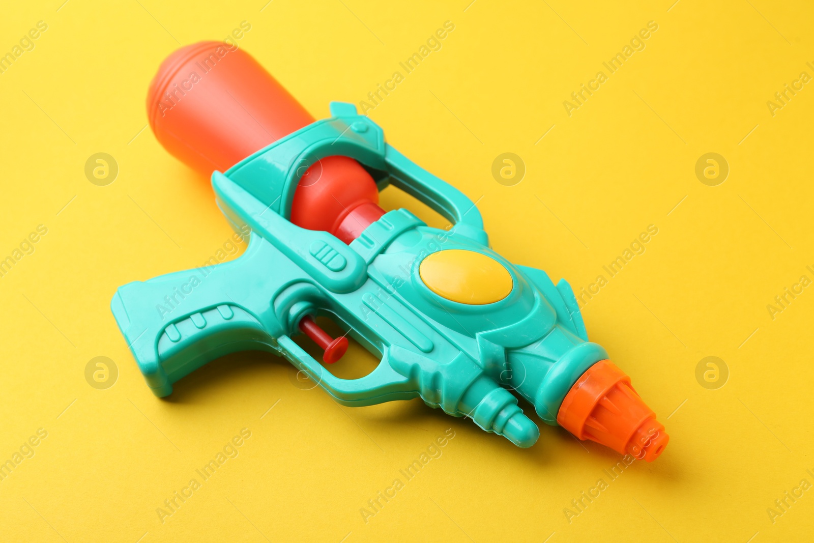 Bright plastic water gun on yellow background, closeup Photo of Bright plastic water gun on yellow background, closeup