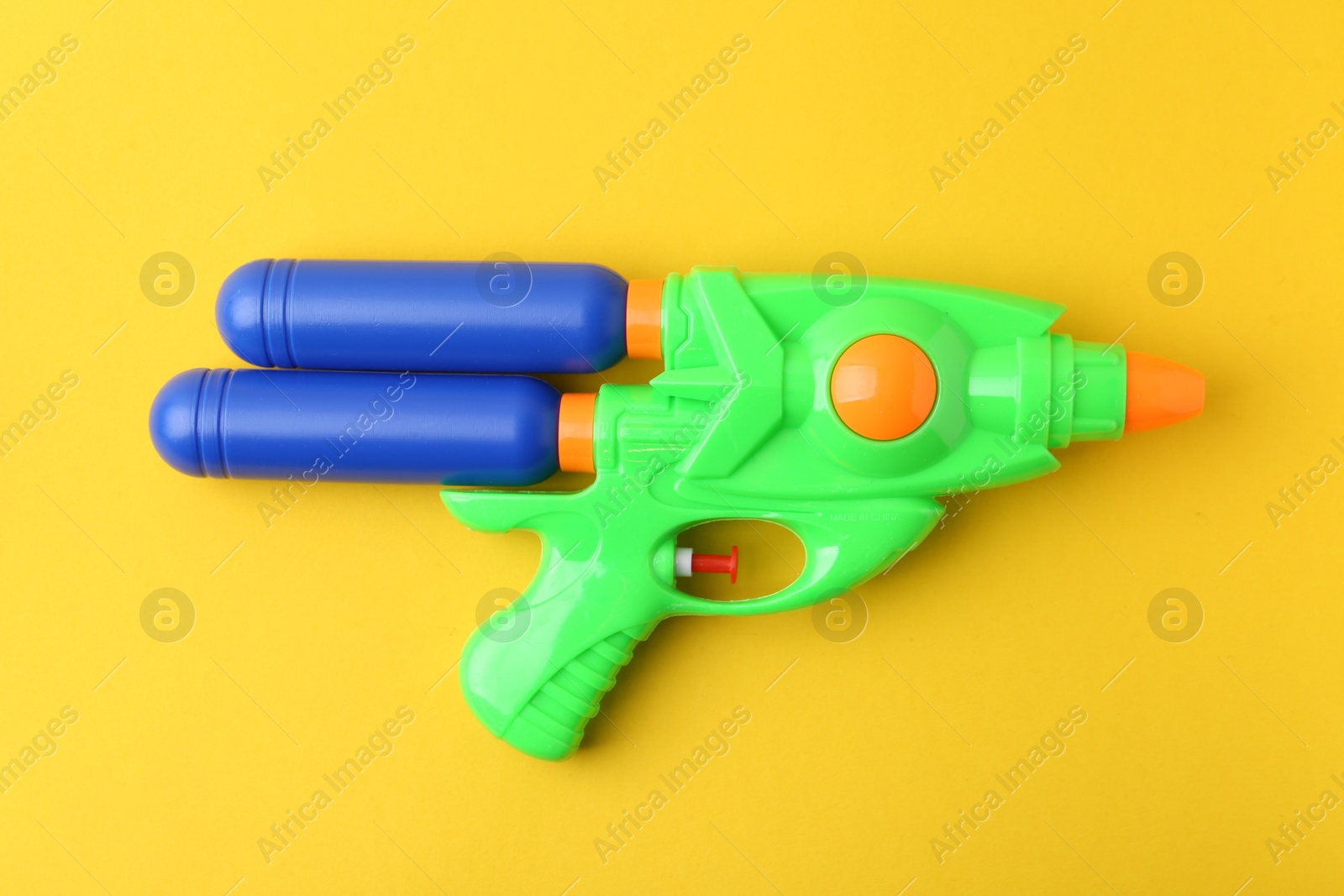 Bright plastic water gun on yellow background, top view Photo of Bright plastic water gun on yellow background, top view