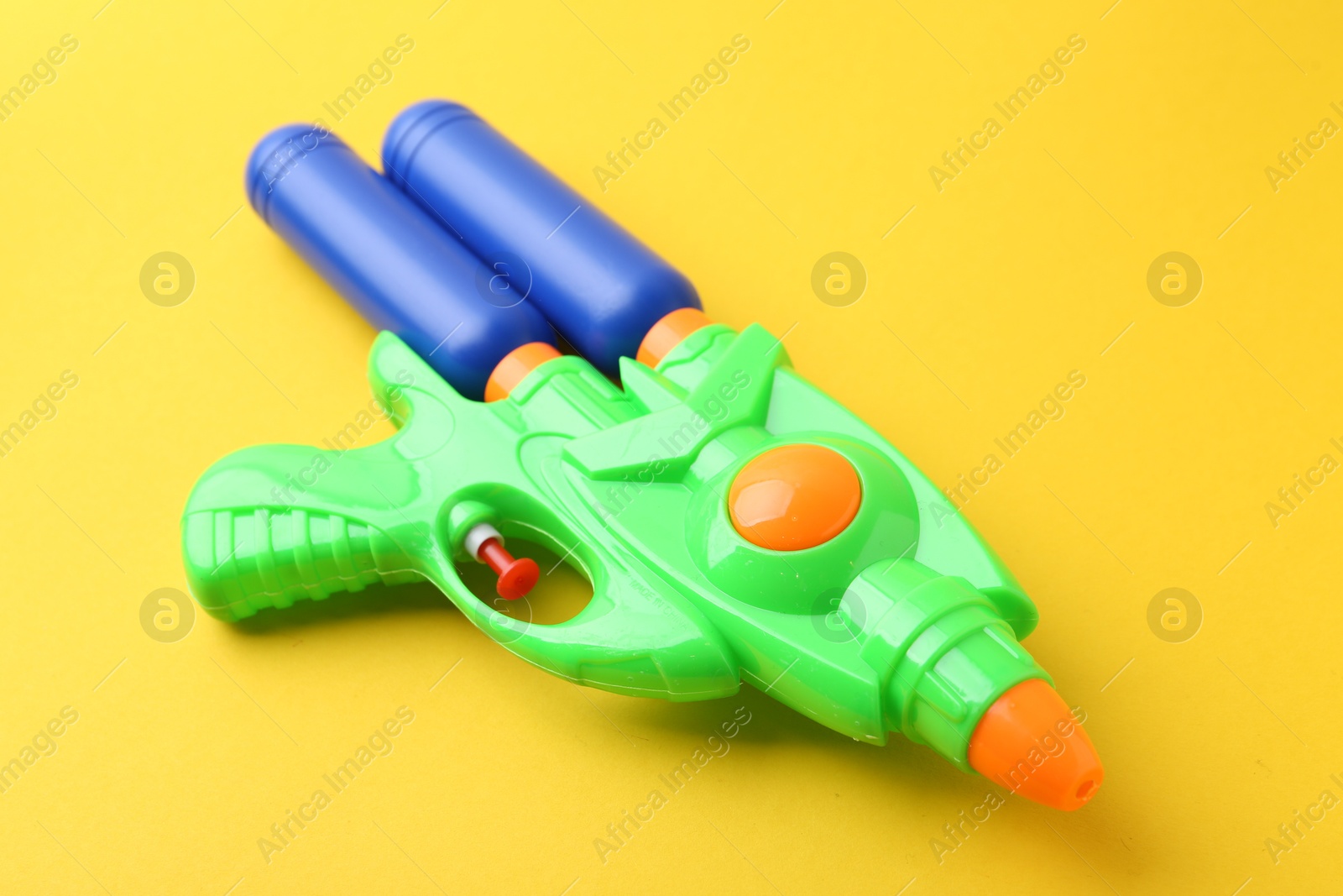 Bright plastic water gun on yellow background, closeup Photo of Bright plastic water gun on yellow background, closeup