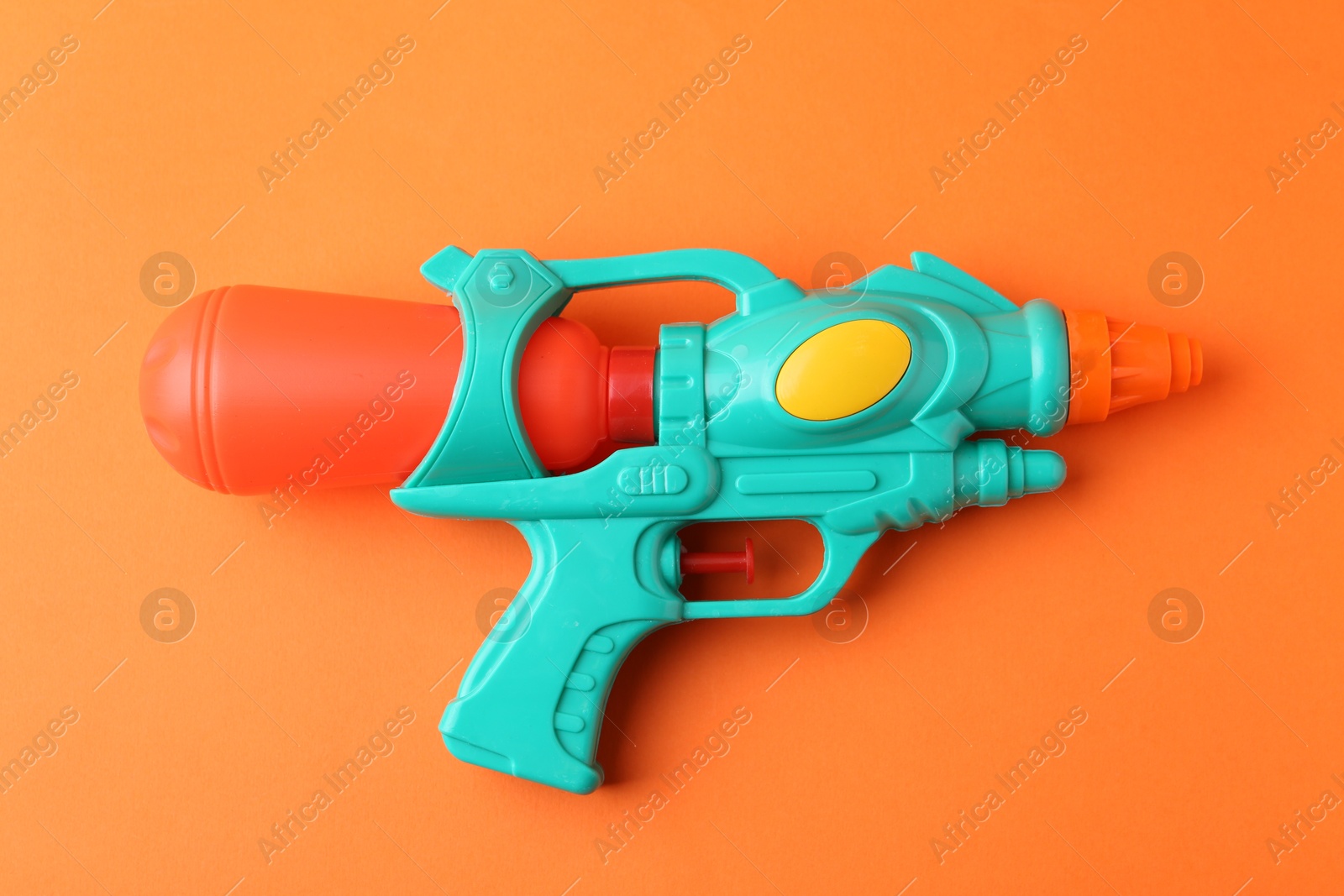 Bright plastic water gun on orange background, top view Photo of Bright plastic water gun on orange background, top view