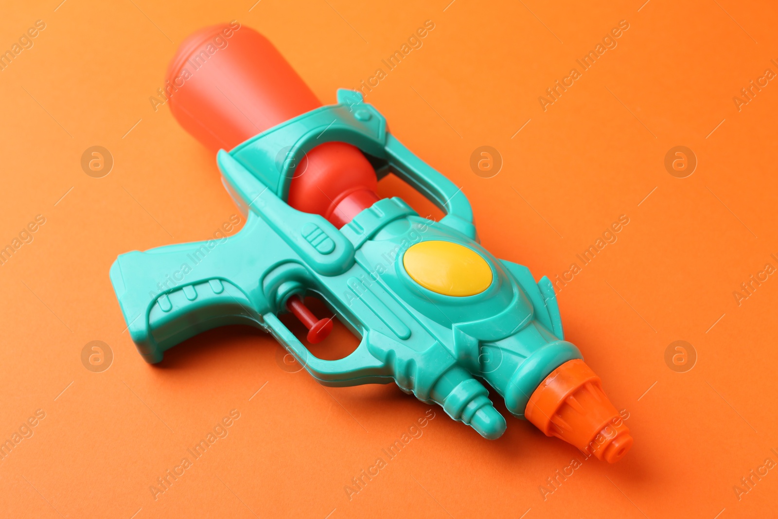 Bright plastic water gun on orange background, closeup Photo of Bright plastic water gun on orange background, closeup