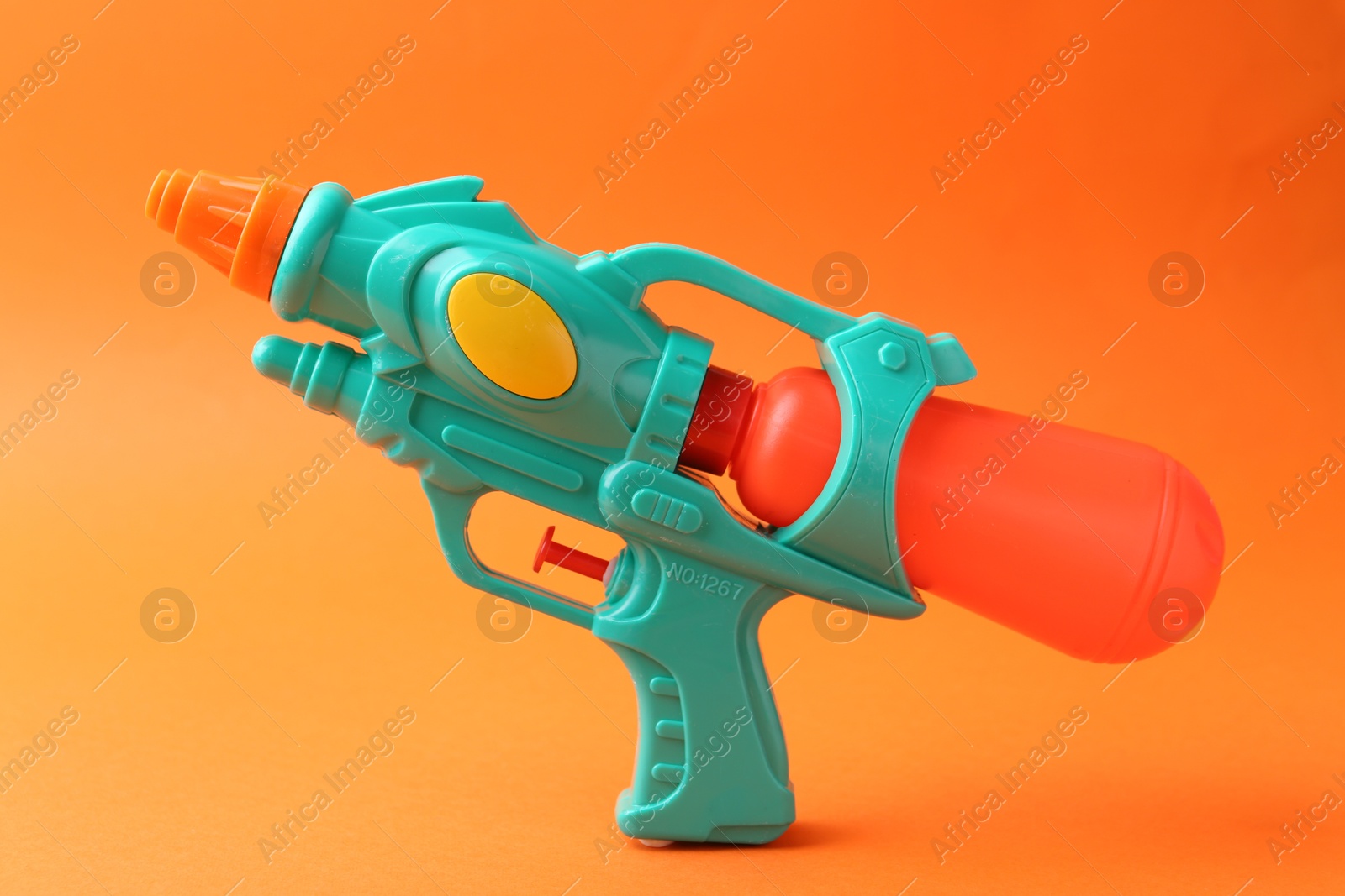 Bright plastic water gun on orange background Photo of Bright plastic water gun on orange background