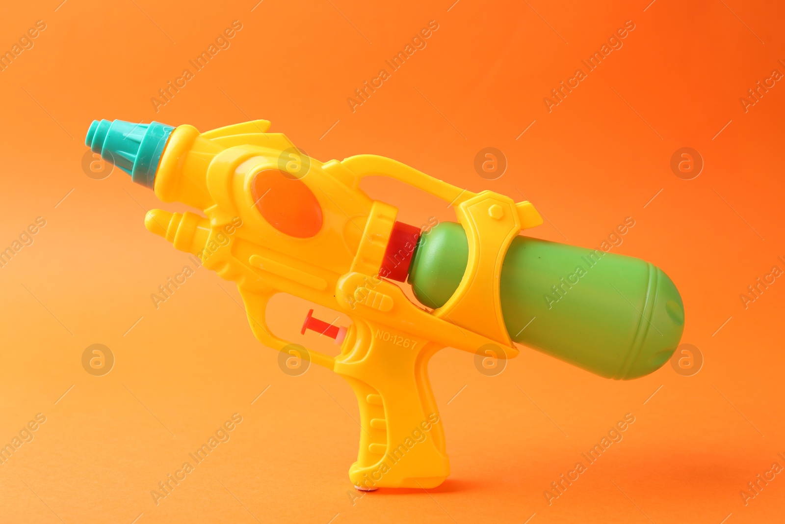 Bright plastic water gun on orange background Photo of Bright plastic water gun on orange background