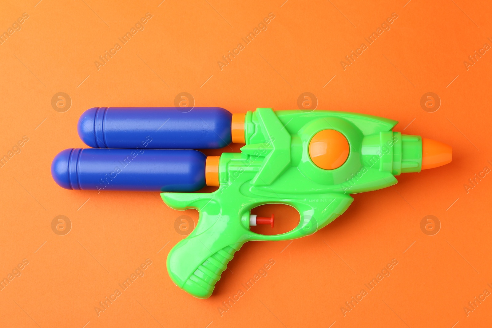 Bright plastic water gun on orange background, top view Photo of Bright plastic water gun on orange background, top view