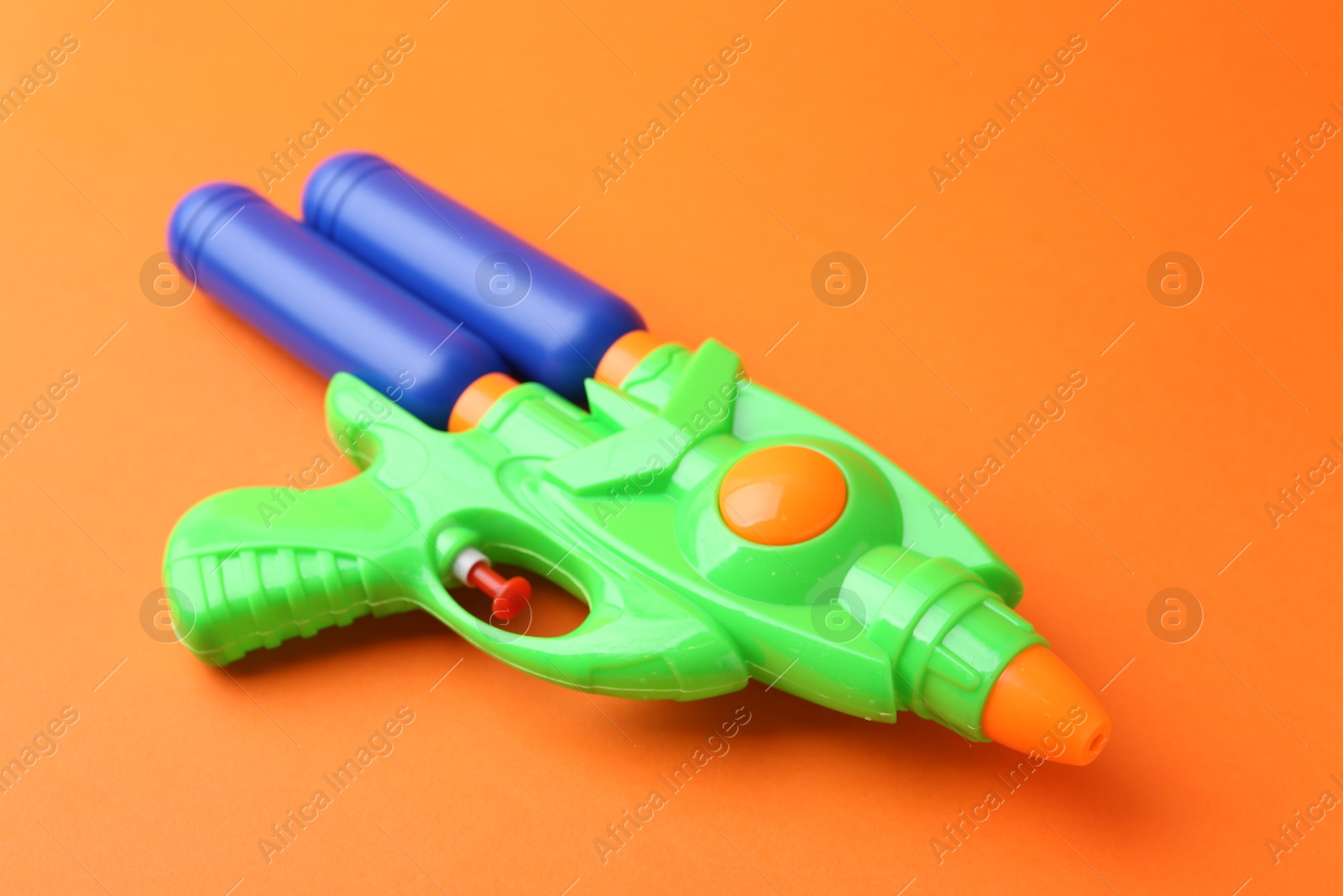 Bright plastic water gun on orange background, closeup Photo of Bright plastic water gun on orange background, closeup