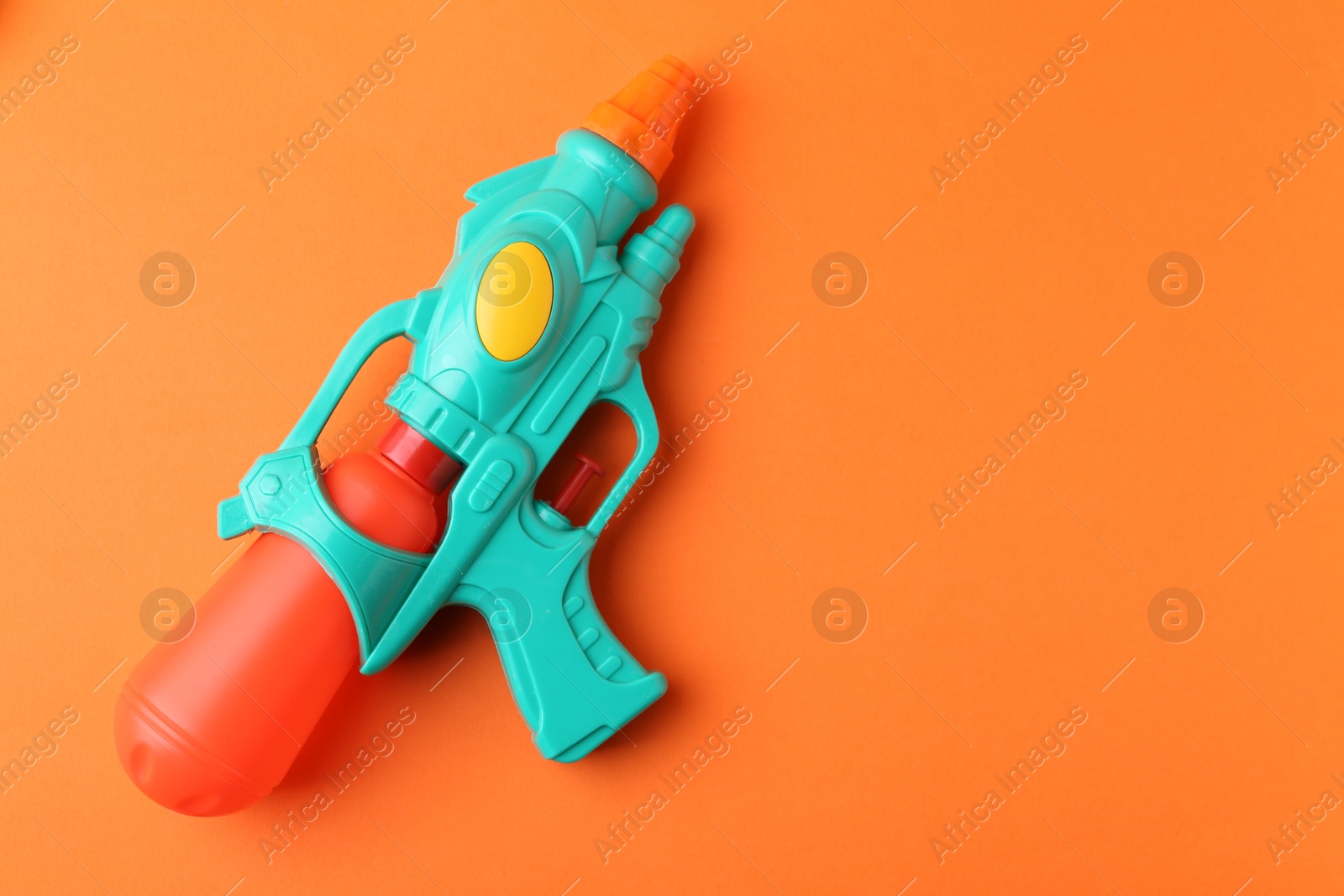 Bright plastic water gun on orange background, top view. Space for text Photo of Bright plastic water gun on orange background, top view. Space for text