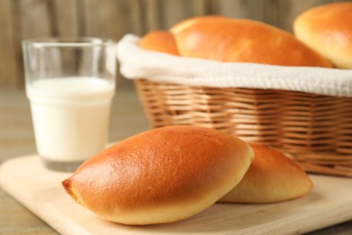 Photo of Tasty baked patties and milk on wooden table, closeup