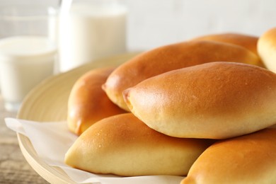 Photo of Tasty baked patties and milk on wooden table, closeup