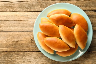 Photo of Tasty baked patties on wooden table, top view. Space for text