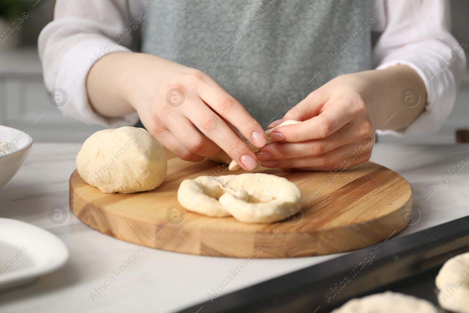 Woman shaping pretzels at table in kitchen, closeup Photo of Woman shaping pretzels at table in kitchen, closeup
