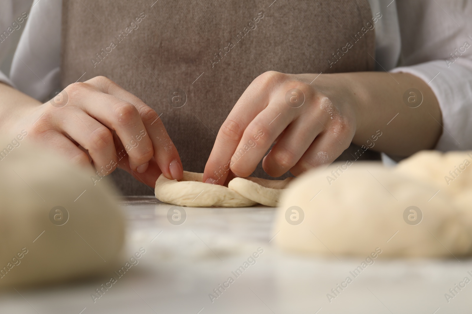 Woman shaping pretzels at table in kitchen, closeup Photo of Woman shaping pretzels at table in kitchen, closeup